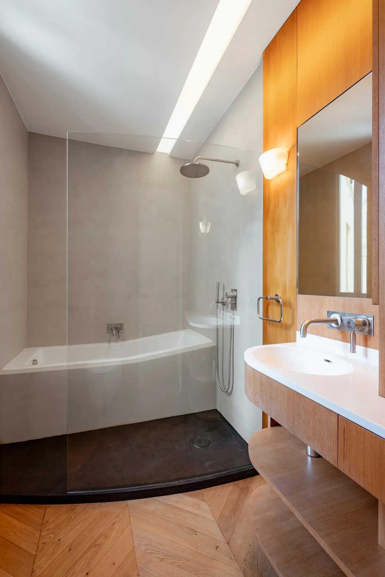 Salle de bains en béton ciré, baignoire et meuble en bois.