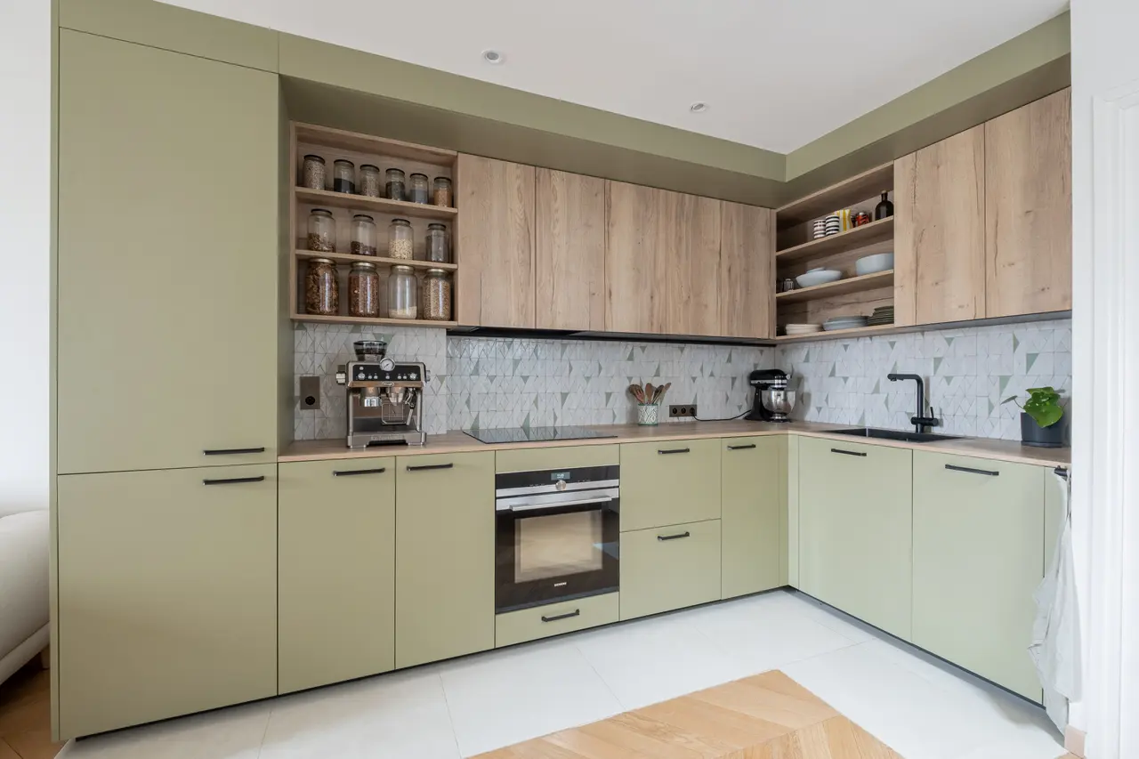 La cuisine en L, façades vert sauge et chêne.