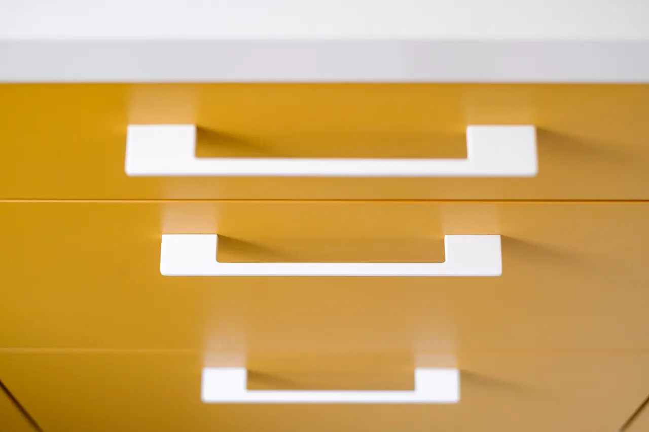 Détail des poignées blanches sur la laque ocre.