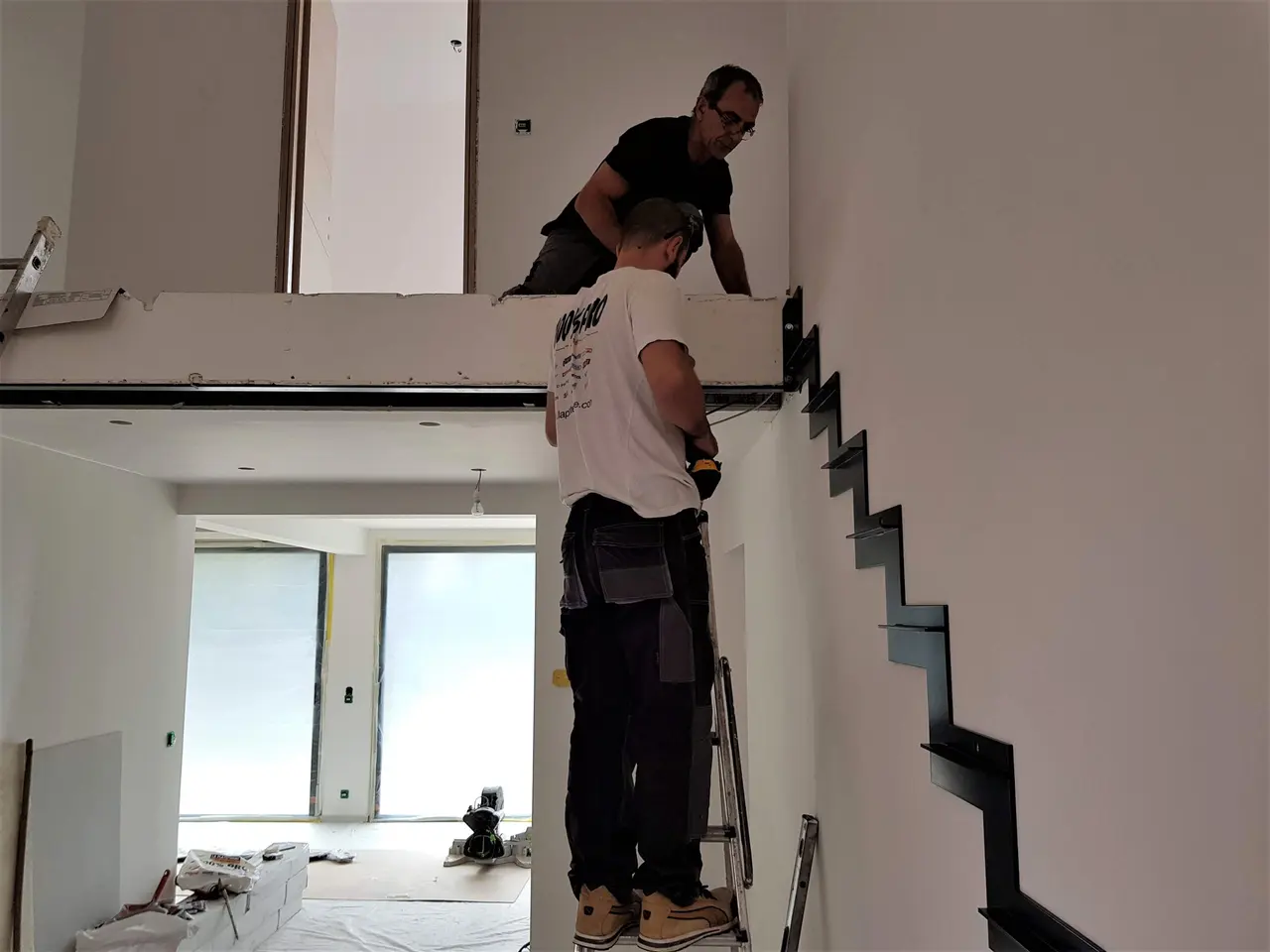 Deux compagnons posent le limon du nouvel escalier.