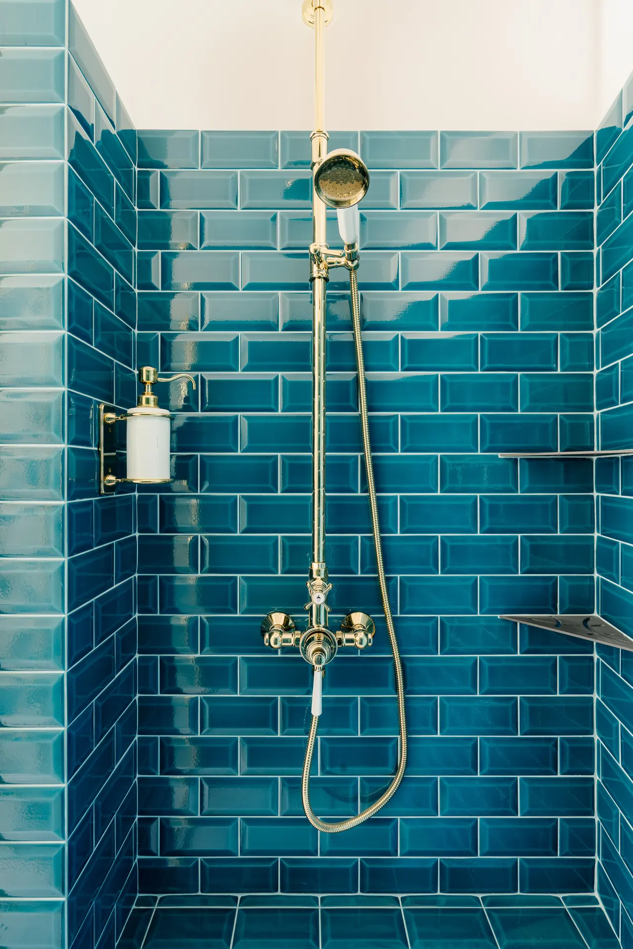 Carreaux métro bleus et robinetterie laiton dans la douche.