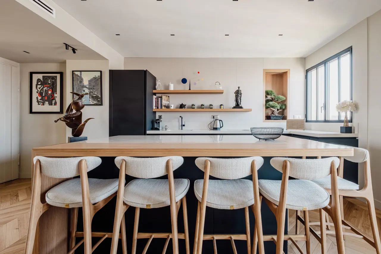 Cuisine de l'avenue de Suffren : îlot en chêne et chaises claires, façades noires.