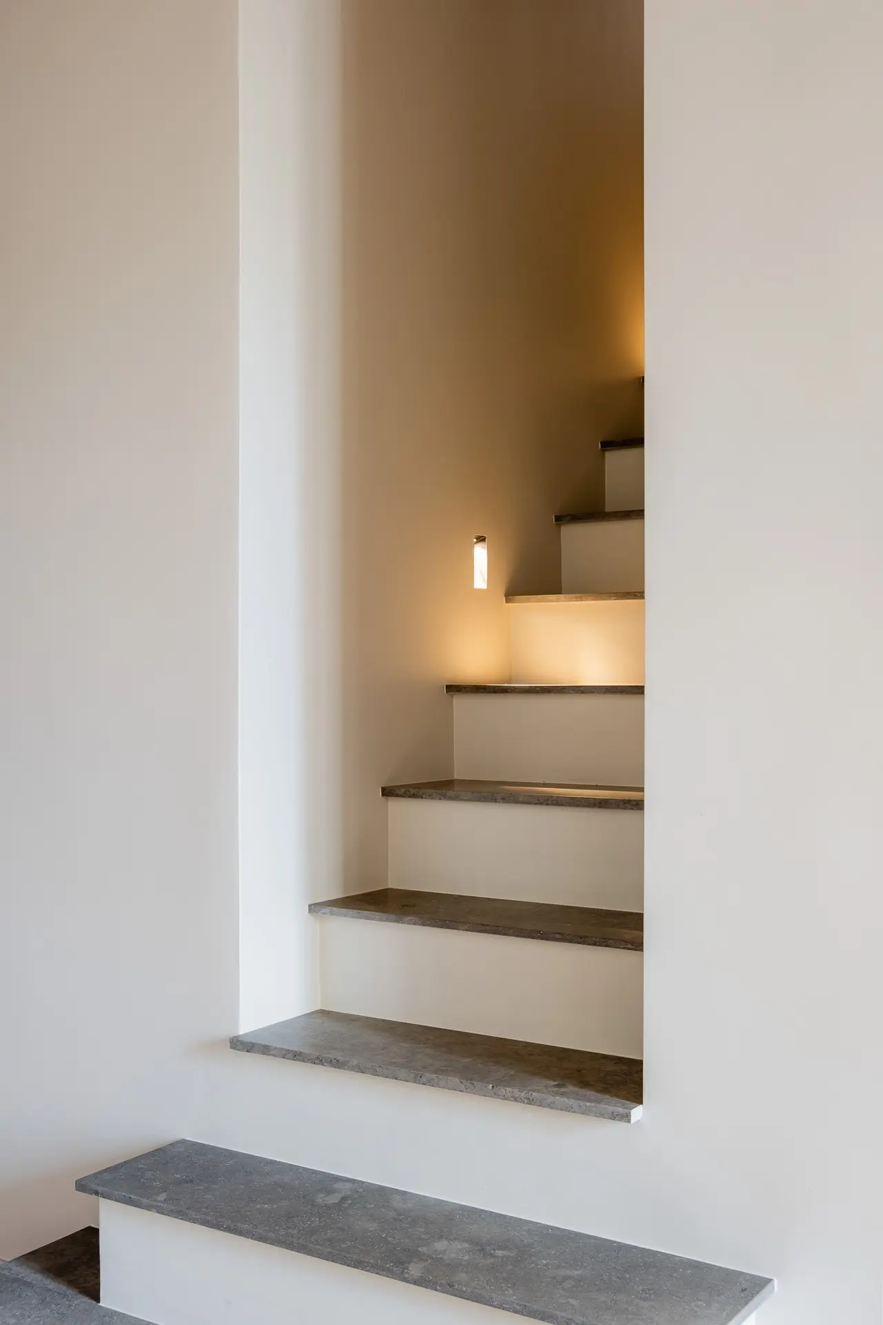 Marches en pierre de l'escalier, éclairées par une niche.