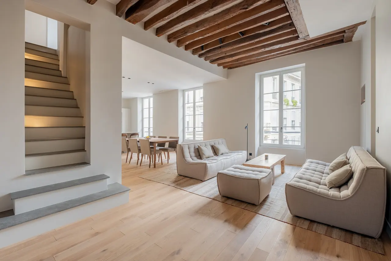 Séjour du duplex de la rue du Temple : poutres anciennes, parquet en chêne, l'escalier à gauche.