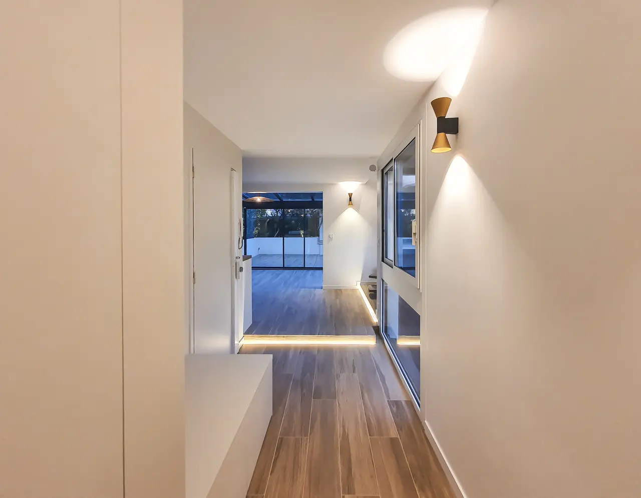 Couloir éclairé, parquet clair.